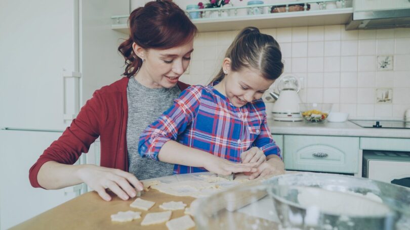 A mother and daughter bake cookies together in the kitchen.