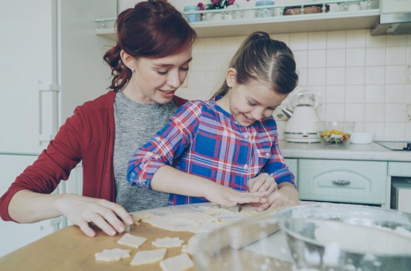 A mother and daughter bake cookies together in the kitchen.